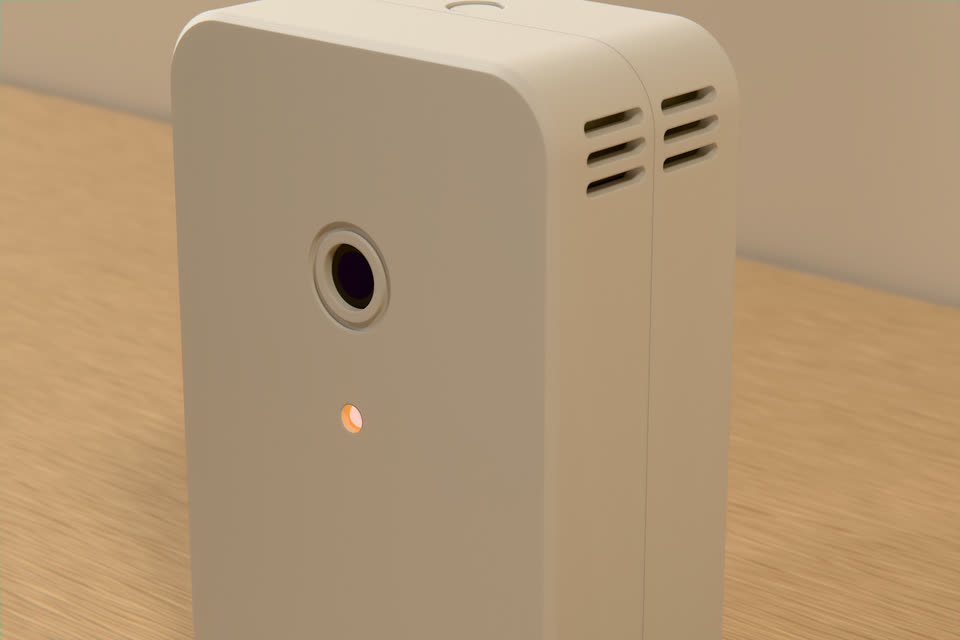Close-up of the R-01: the round eye with its debossed ring, the orange status light, the seam between the two trays and the vent slots on the side.